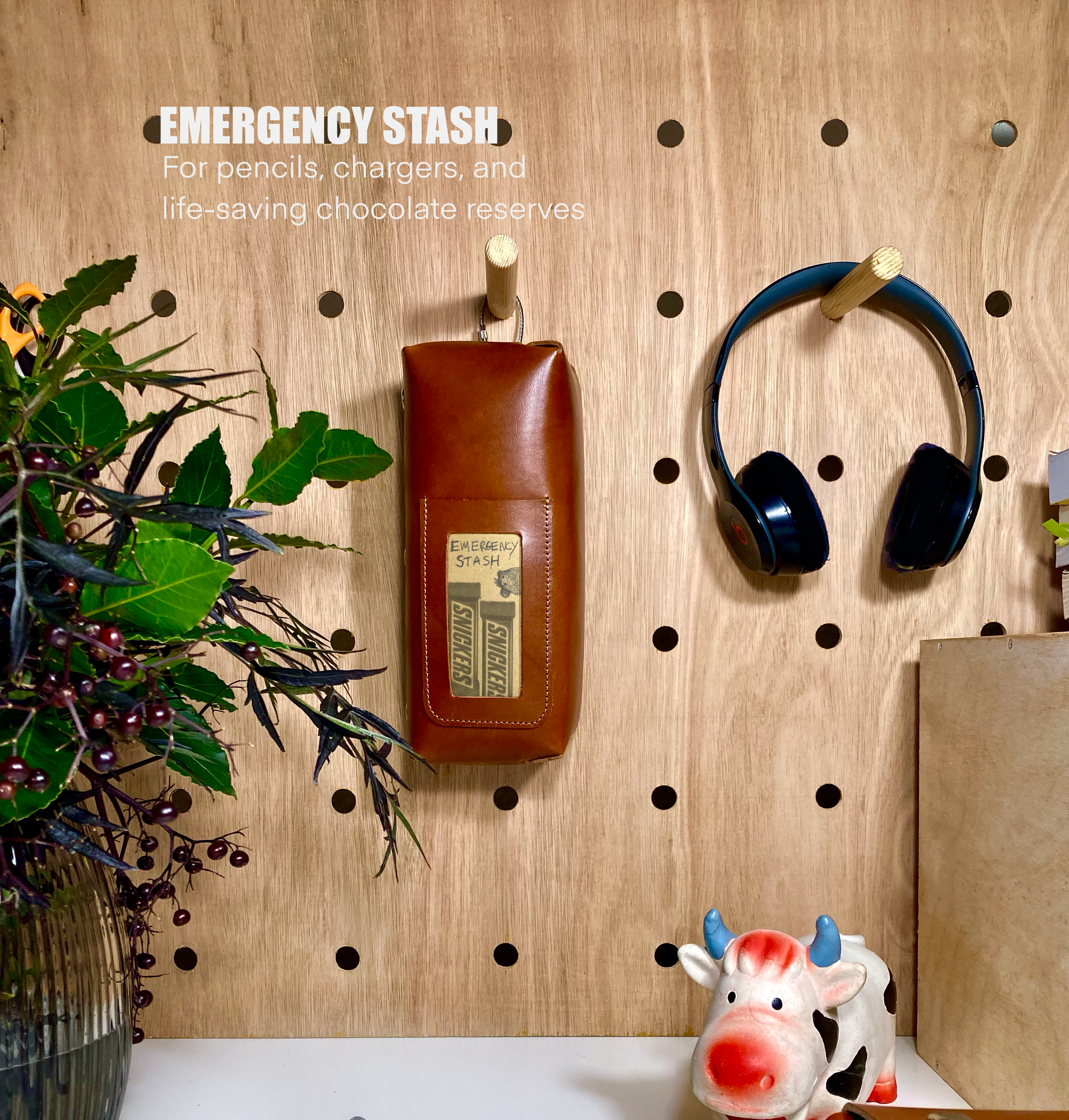 Pegboard with various items including a brown bag, black headphones, and a cow-shaped container.